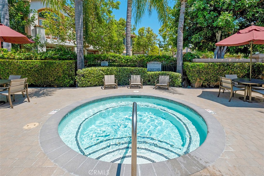 Outdoor spa with a central handrail, surrounded by a tiled patio and seating.