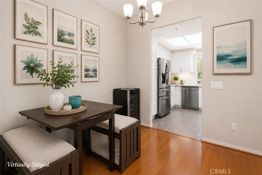 Dining area with a dark wood table and upholstered benches opens into a bright white kitchen.