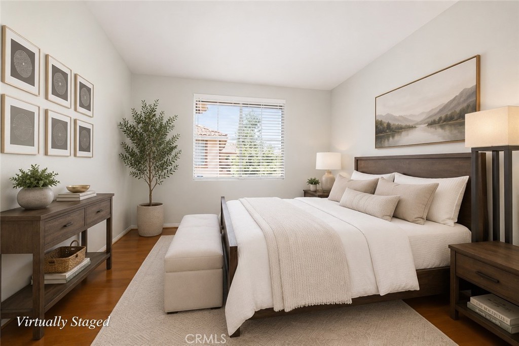 Virtually staged bedroom with a dark wood bed, neutral bedding, bench, and framed art.