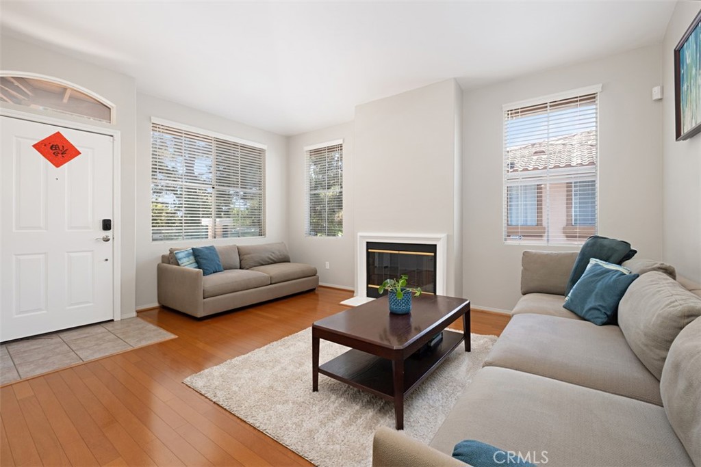 Furnished living room with a fireplace, two gray sofas, and hardwood floors.