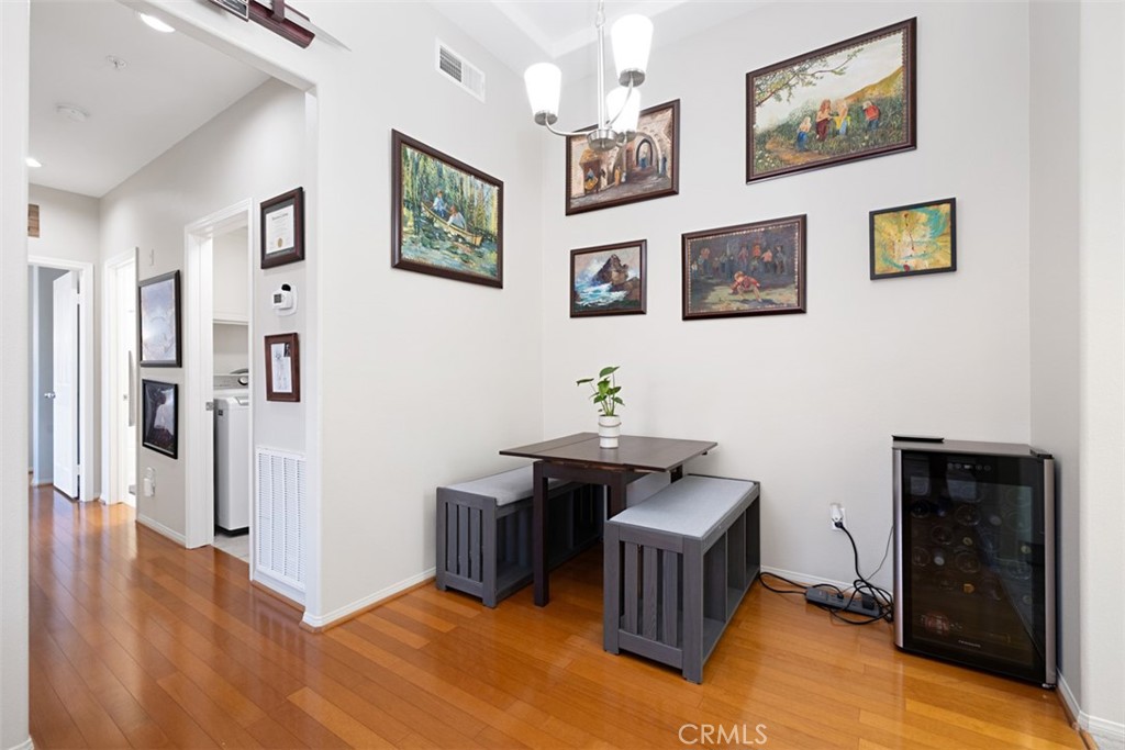 Dining nook with a dark table and benches, framed artwork, and a glass-front wine refrigerator.