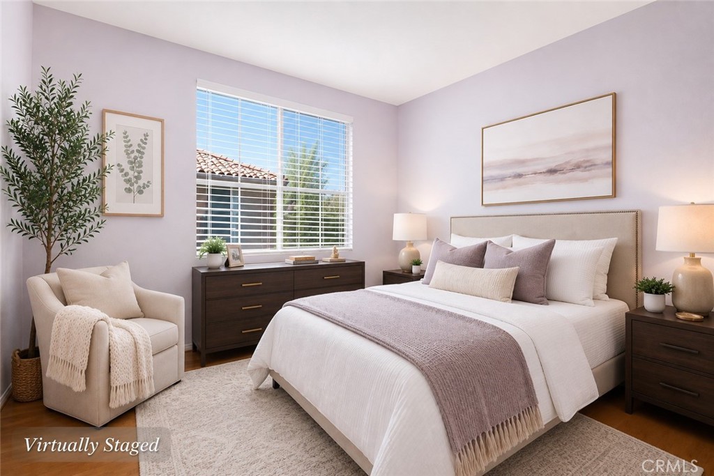 Virtually staged bedroom with a white bed, mauve accents, dark wood furniture, and a wide window.