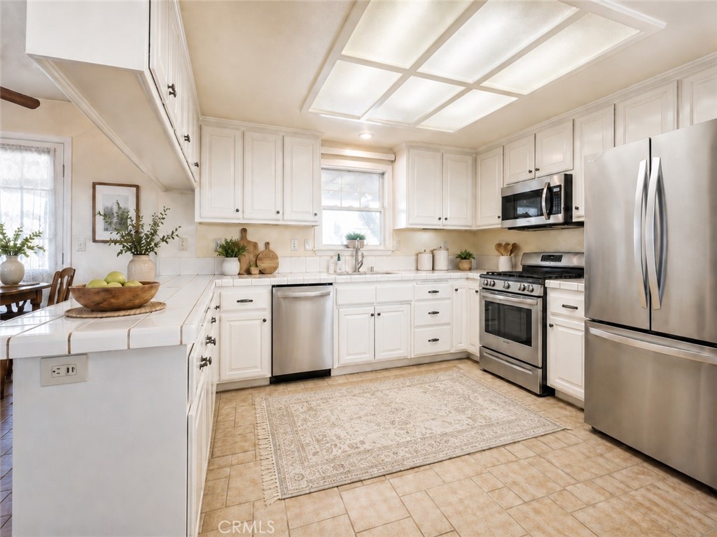 Kitchen with white cabinetry, stainless steel appliances, and a large grid-style ceiling light.