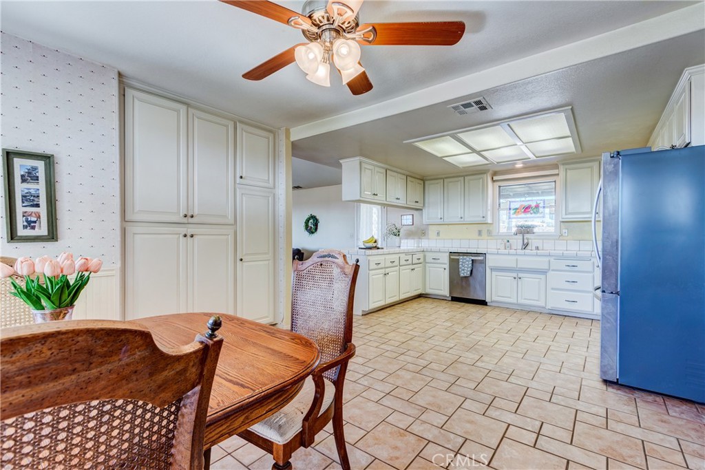 Kitchen with white cabinets, blue refrigerator, and a wooden dining table in the foreground.