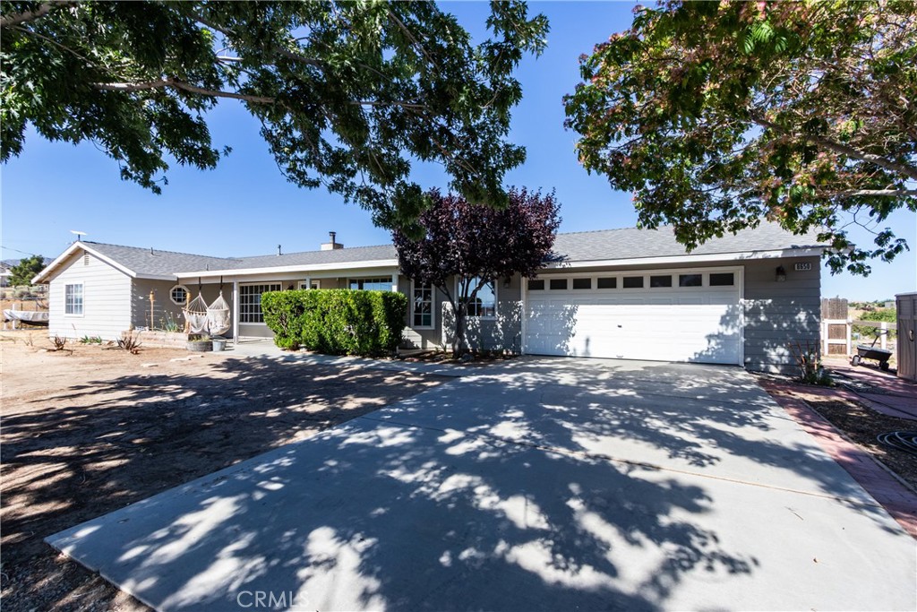 Single-story home with an attached garage and a broad, tree-shaded driveway.