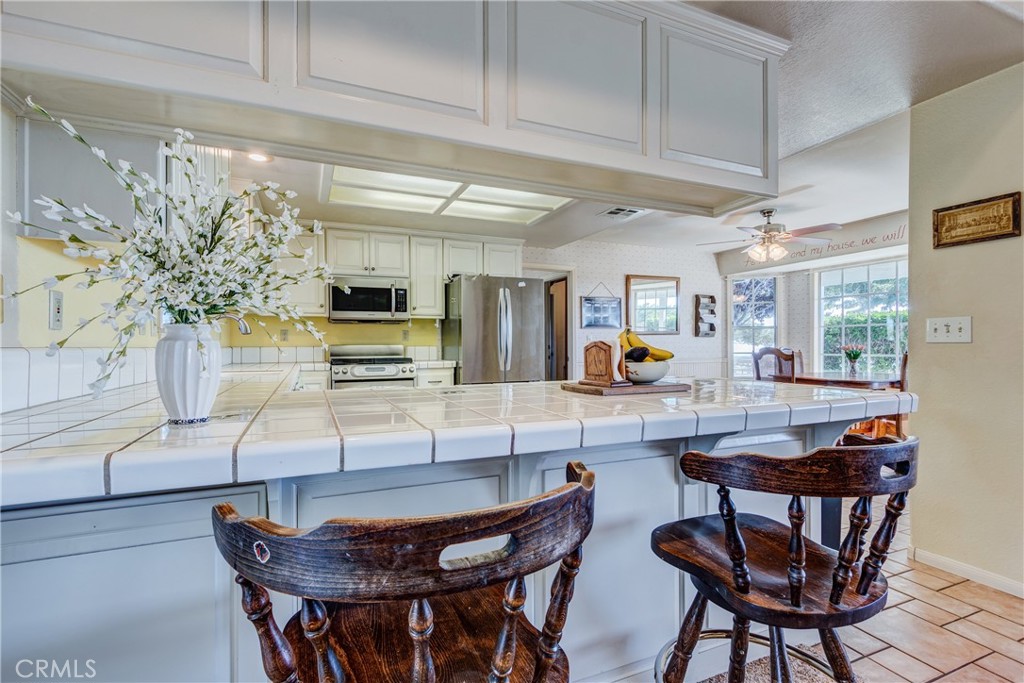 Kitchen with a large tiled island, dark wooden bar stools, and stainless steel appliances.