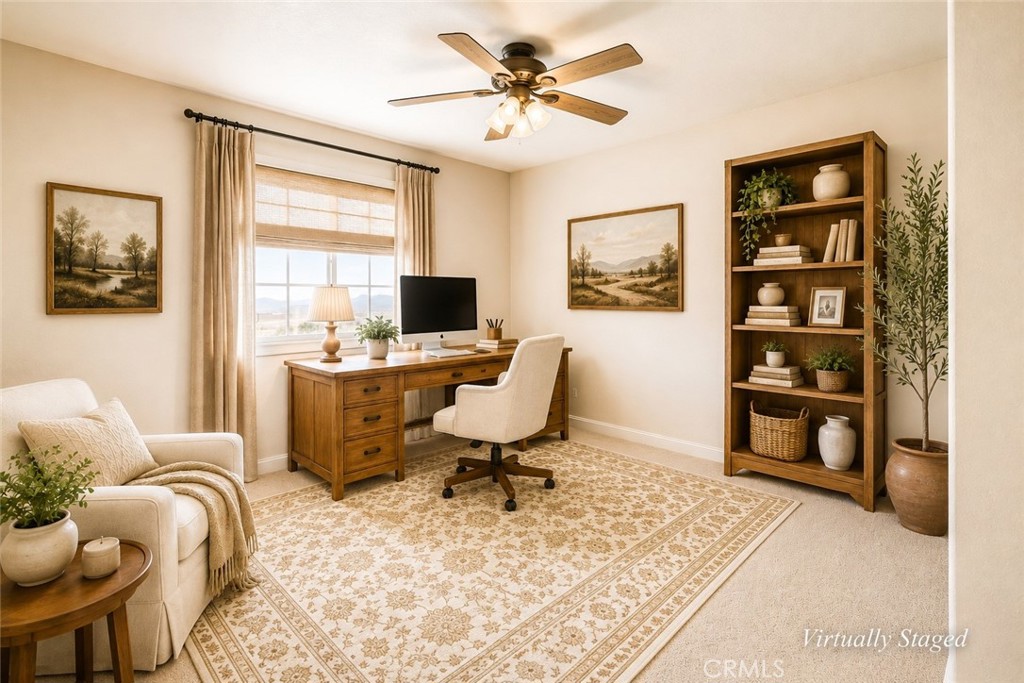 Virtually staged home office with a wooden desk, bookcase, and patterned rug.