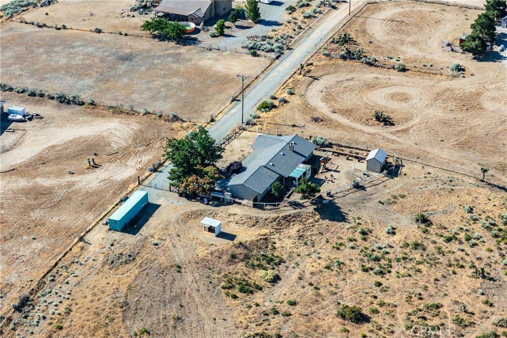 Rural home on dry acreage with outbuildings beside a paved road.