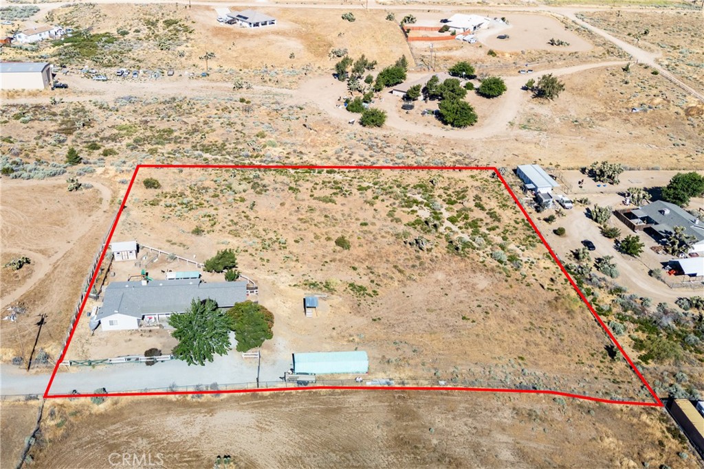 Aerial view of a large rural parcel outlined in red, with a home and outbuildings near the road.