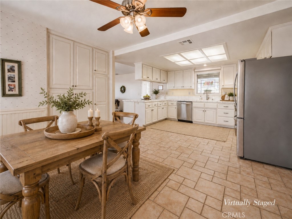 Kitchen and dining area with white cabinetry, stainless steel appliances, and a virtually staged wooden dining table.