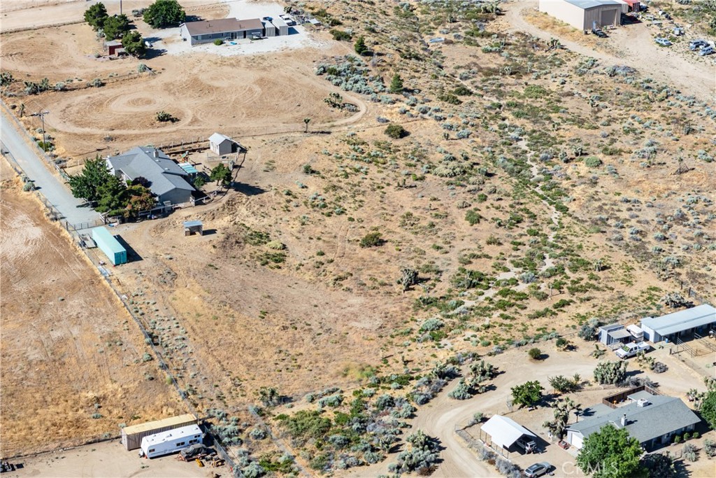 Aerial view of dry, scrub-covered land among scattered rural homes and dirt roads.