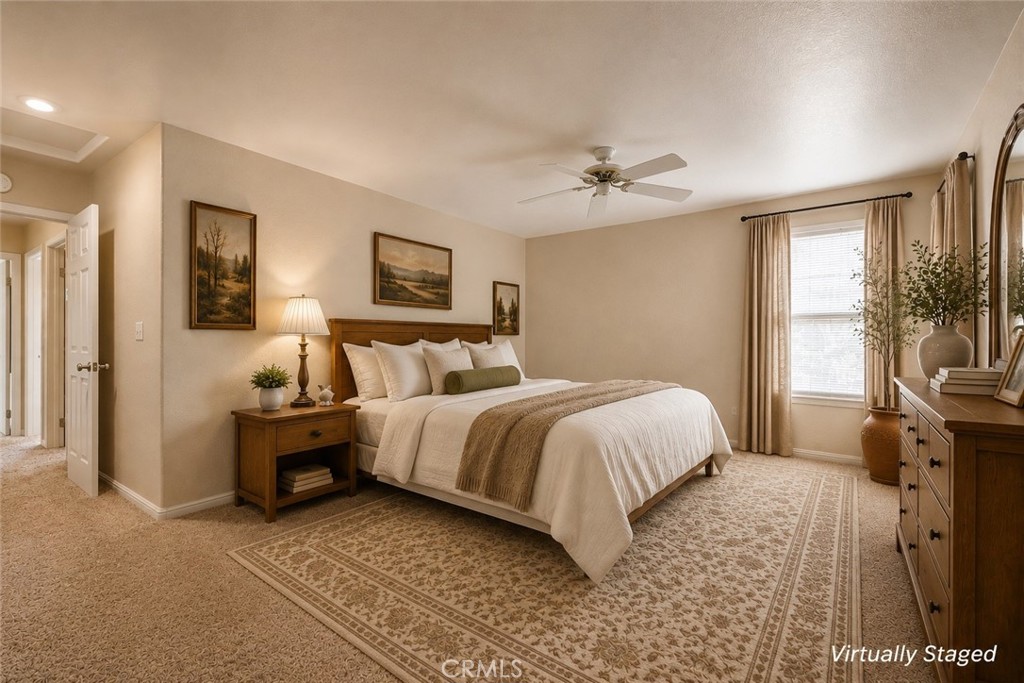 Staged bedroom with a large white bed, patterned rug, and wooden furniture.