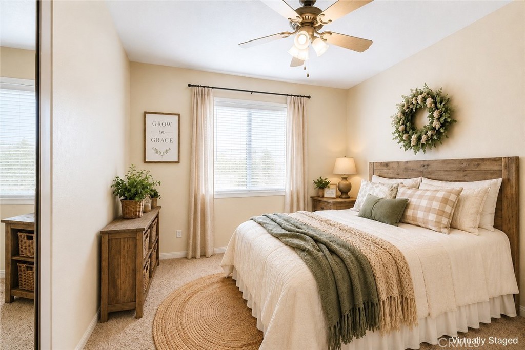 Staged bedroom with a rustic wooden bed, layered neutral bedding, and a green throw.