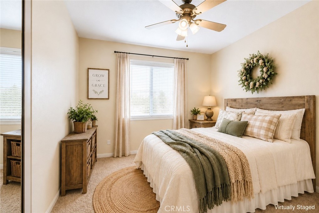 Bedroom with cream and sage bedding, rustic wood headboard, and a sunlit window.