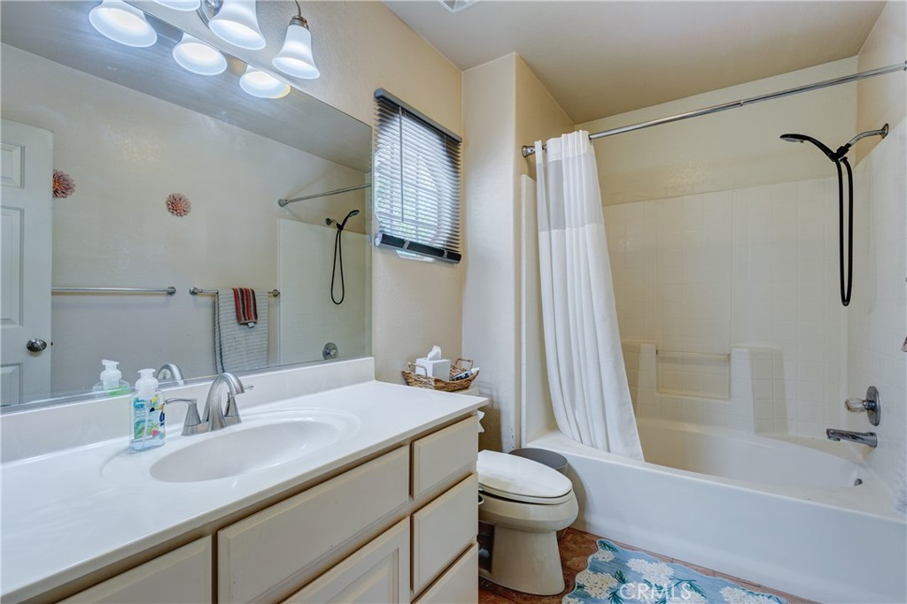 Bathroom with a large mirrored vanity, toilet, and bathtub with a white shower curtain.