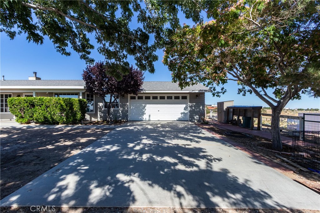 Single-story home with a double garage and broad driveway shaded by mature trees.