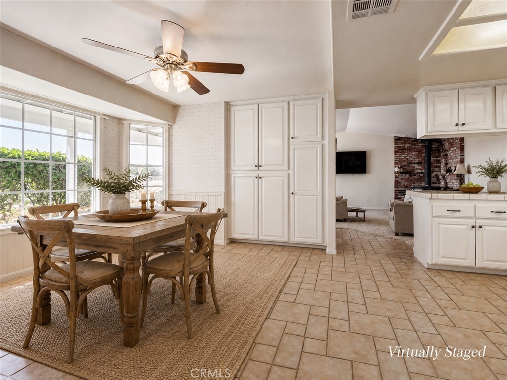 Open kitchen and dining area with white cabinets, a wooden table, and large windows.