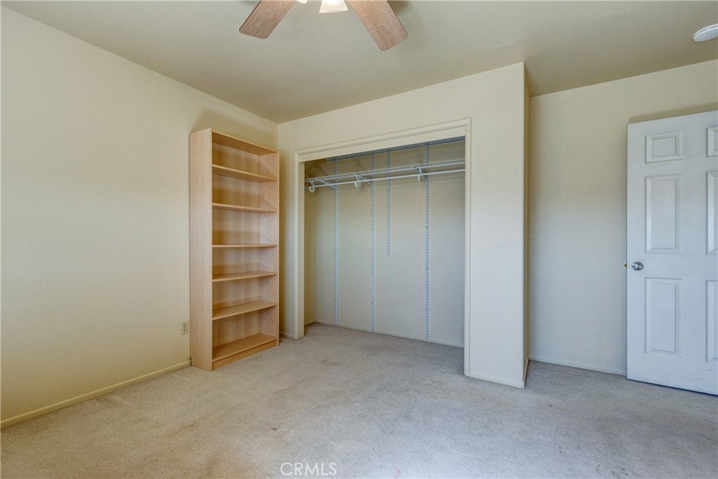Empty bedroom with an open wire-shelf closet and wooden bookcase.