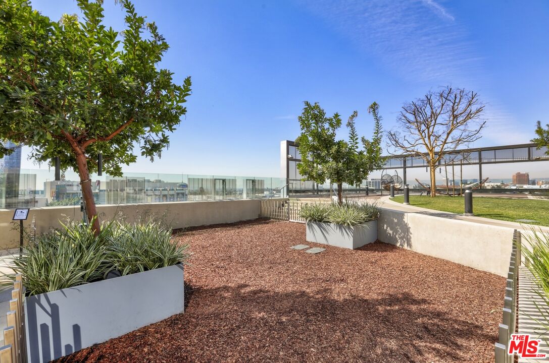 Rooftop terrace with landscaped planters, lounge chairs and distant city views.