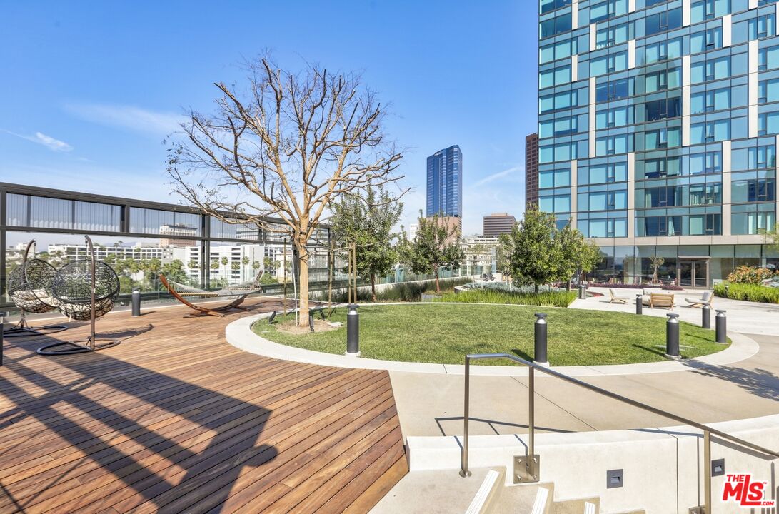 Rooftop deck with a circular lawn, wood-plank seating area, and city buildings.