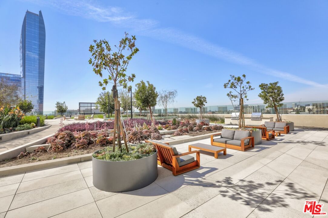 Rooftop terrace with succulent gardens, lounge seating, and a tall glass building in the distance.