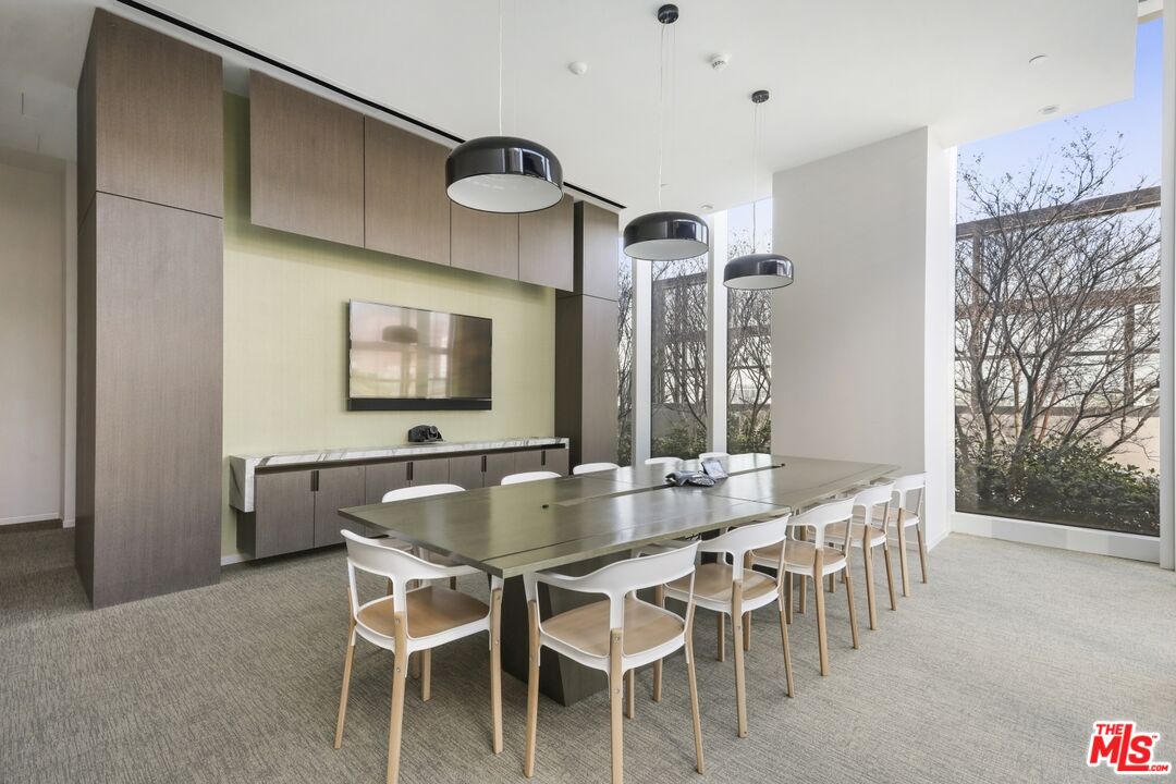 Furnished condo meeting room with a long table, white chairs, built-in cabinetry, and floor-to-ceiling windows.