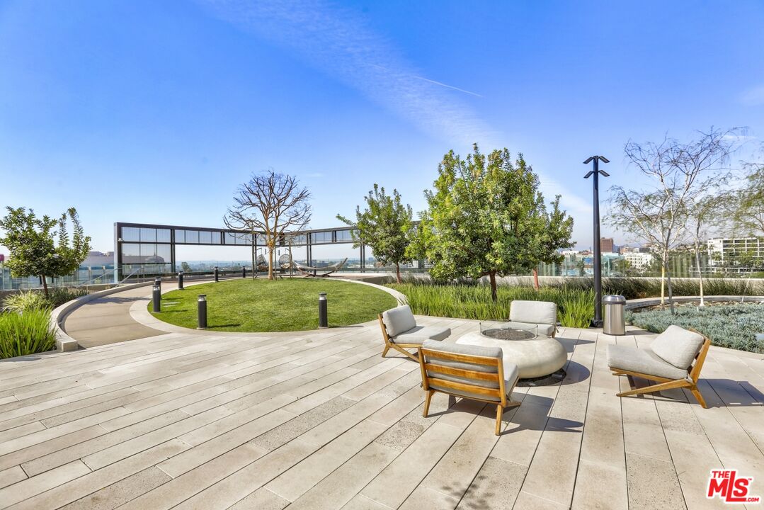 Rooftop terrace with lounge seating around a fire pit and a landscaped lawn overlooking the city.