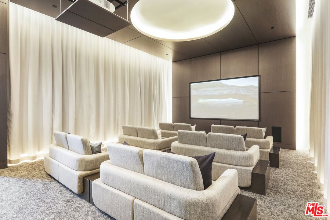 Furnished screening room with rows of lounge seats facing a large screen.