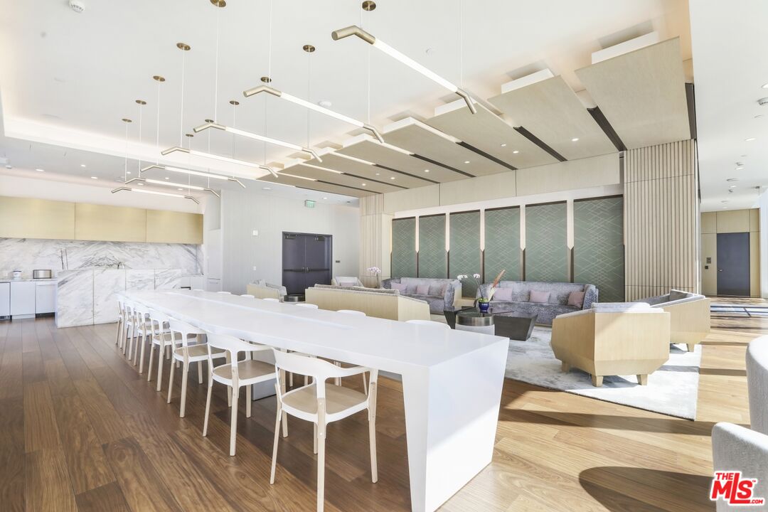 Building lounge with a long white counter, seating area, and marble-accented kitchenette.