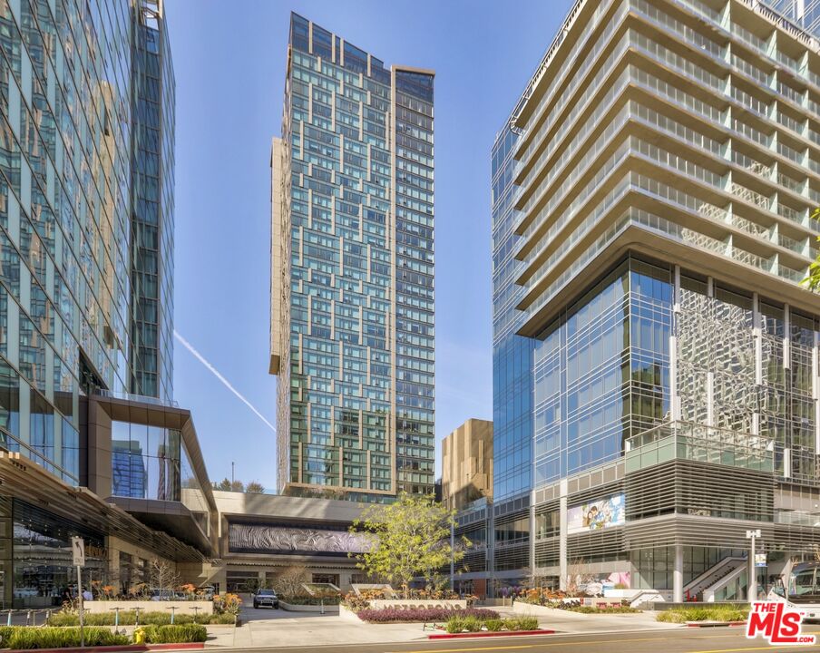 Modern high-rise towers surround a landscaped plaza along the sidewalk.