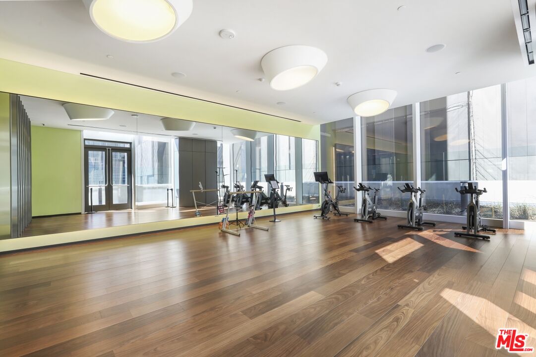 Fitness room with stationary bikes, a mirrored wall, and floor-to-ceiling windows.