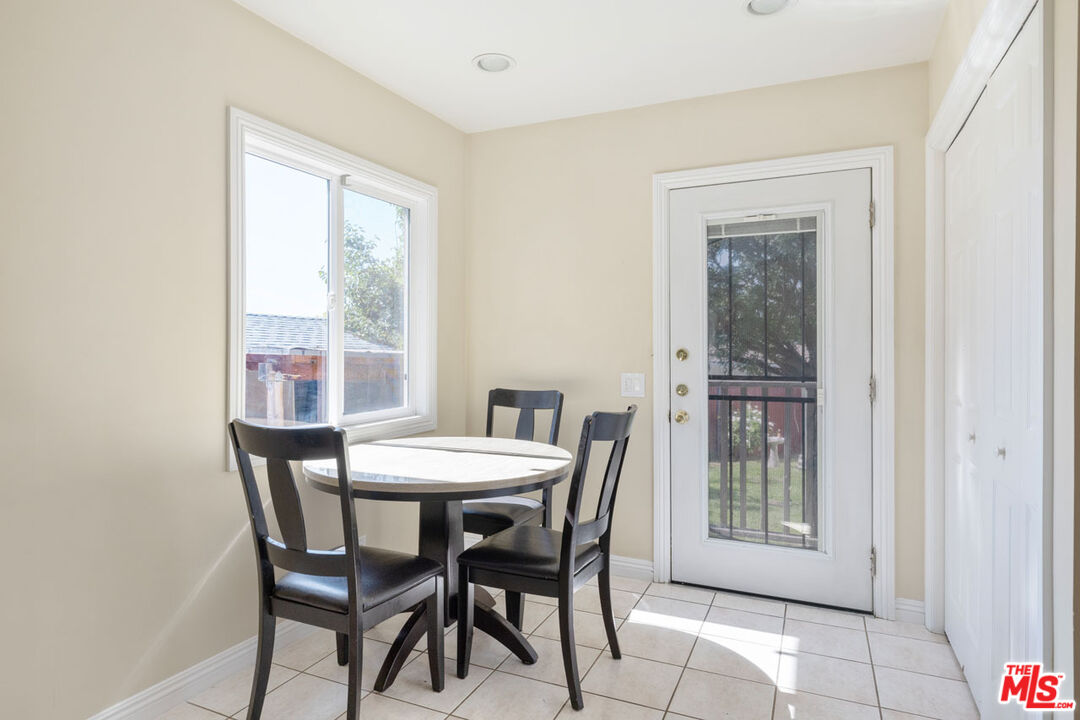 Dining nook with a round table and dark chairs beside a large window and glass-paneled door.