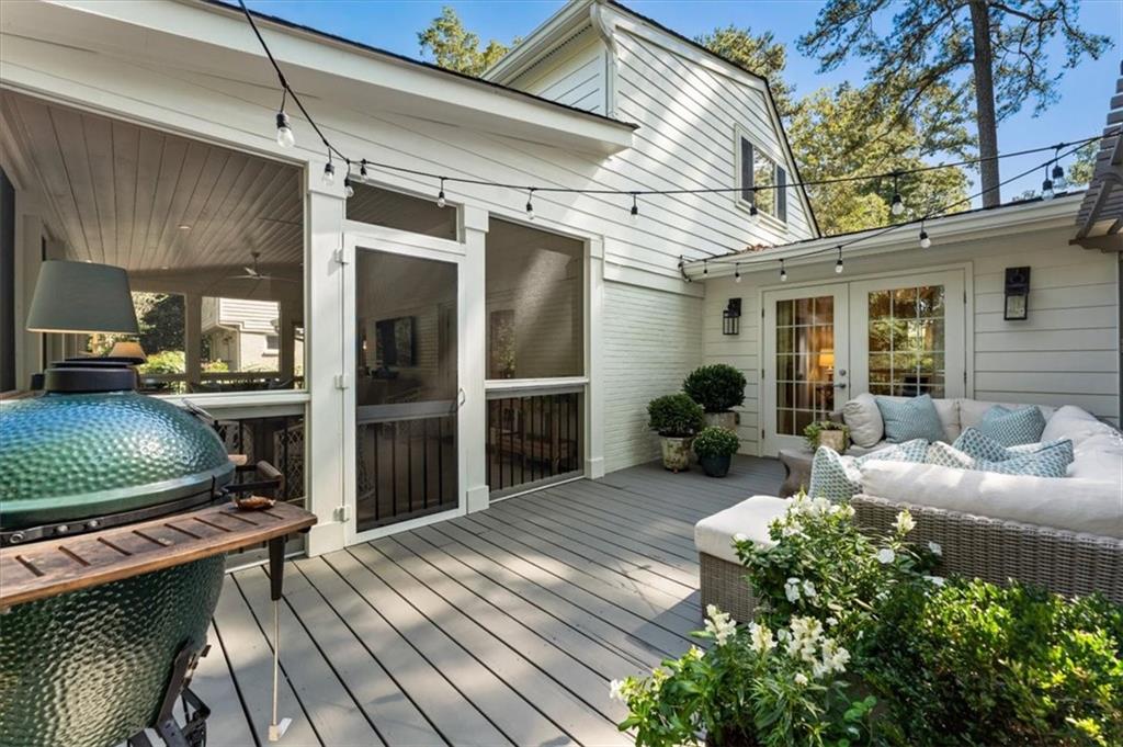 Furnished deck patio with a green ceramic grill, outdoor sofa, and string lights.