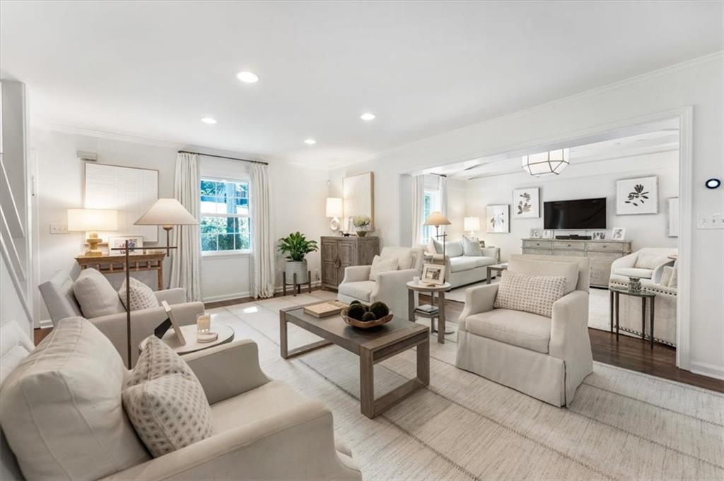 Staged living room with white seating, a wood coffee table, and an adjoining sitting area.