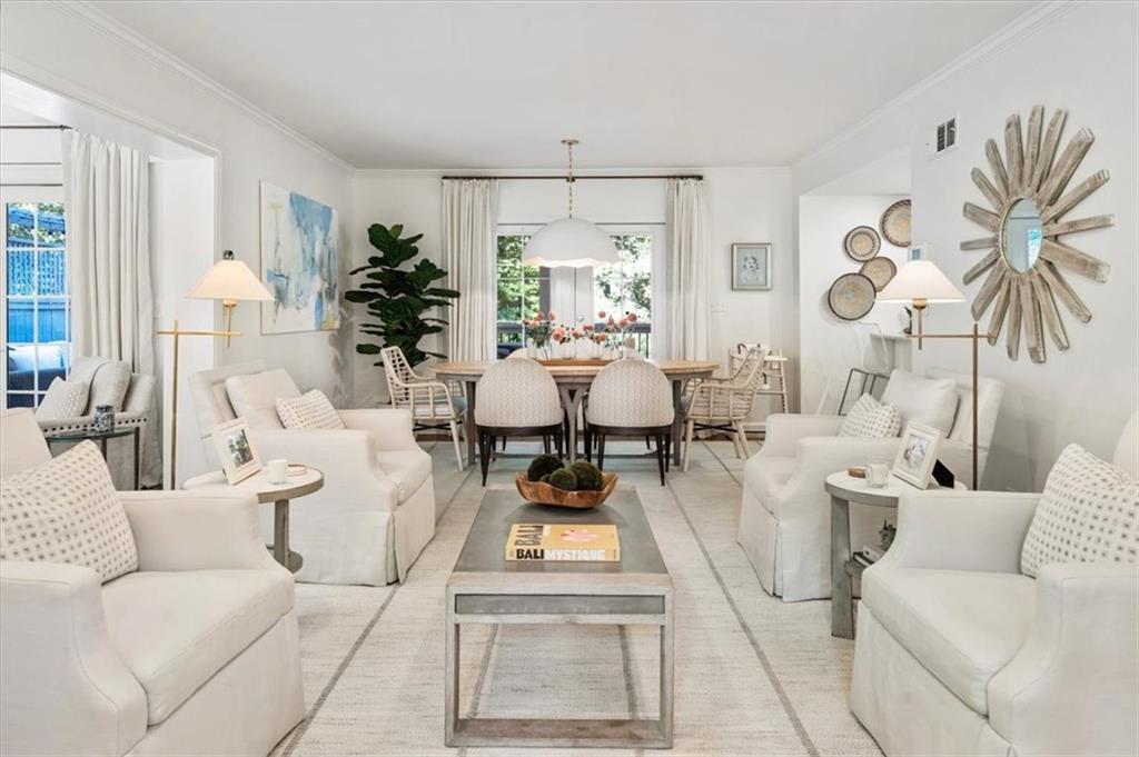 Staged living room with white sofas, a central coffee table, and dining area beyond.