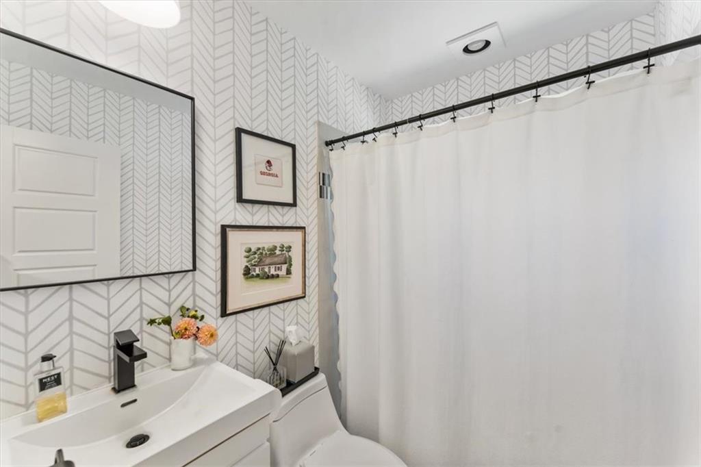 Bathroom with chevron wallpaper, a white vanity, framed artwork, and a white shower curtain.