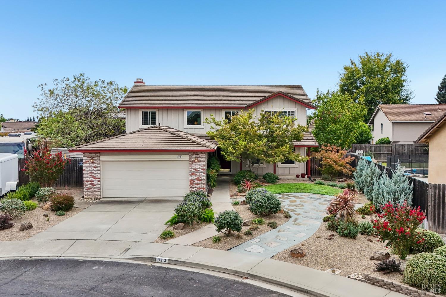 Two-story house with an attached garage, landscaped front yard, and curved stone walkway.