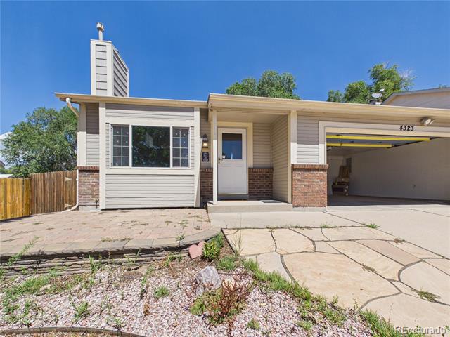 Single-story home with an attached open garage, brick accents, and a fenced yard.