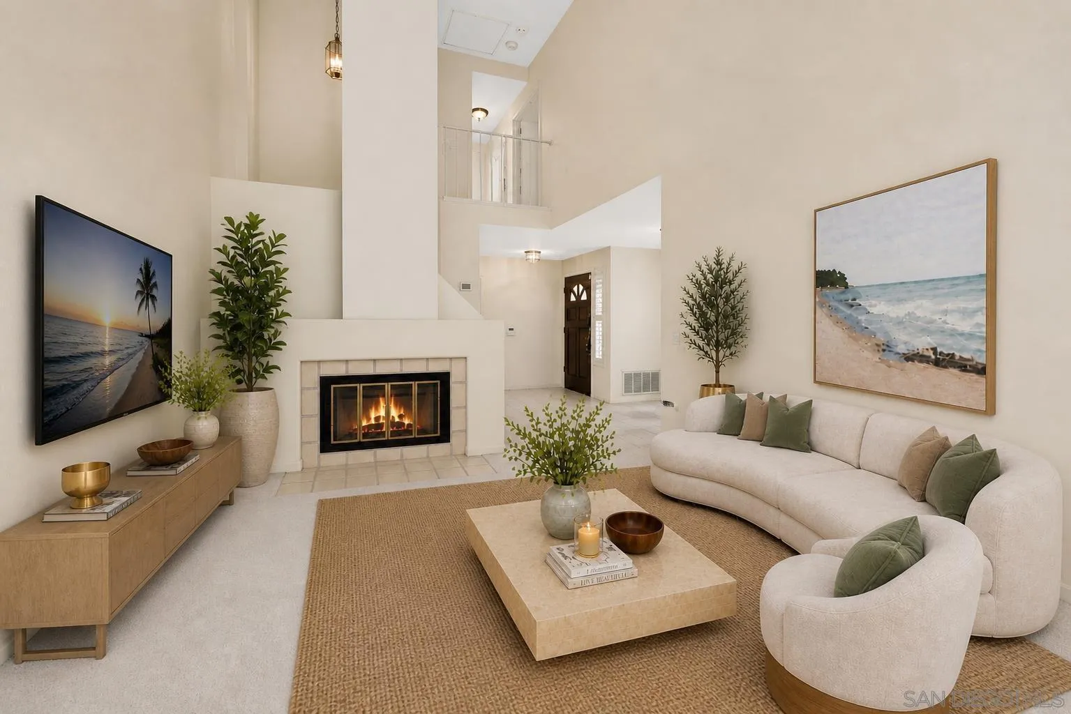 Staged living room with a fireplace, curved cream sectional, and open upper-level landing.