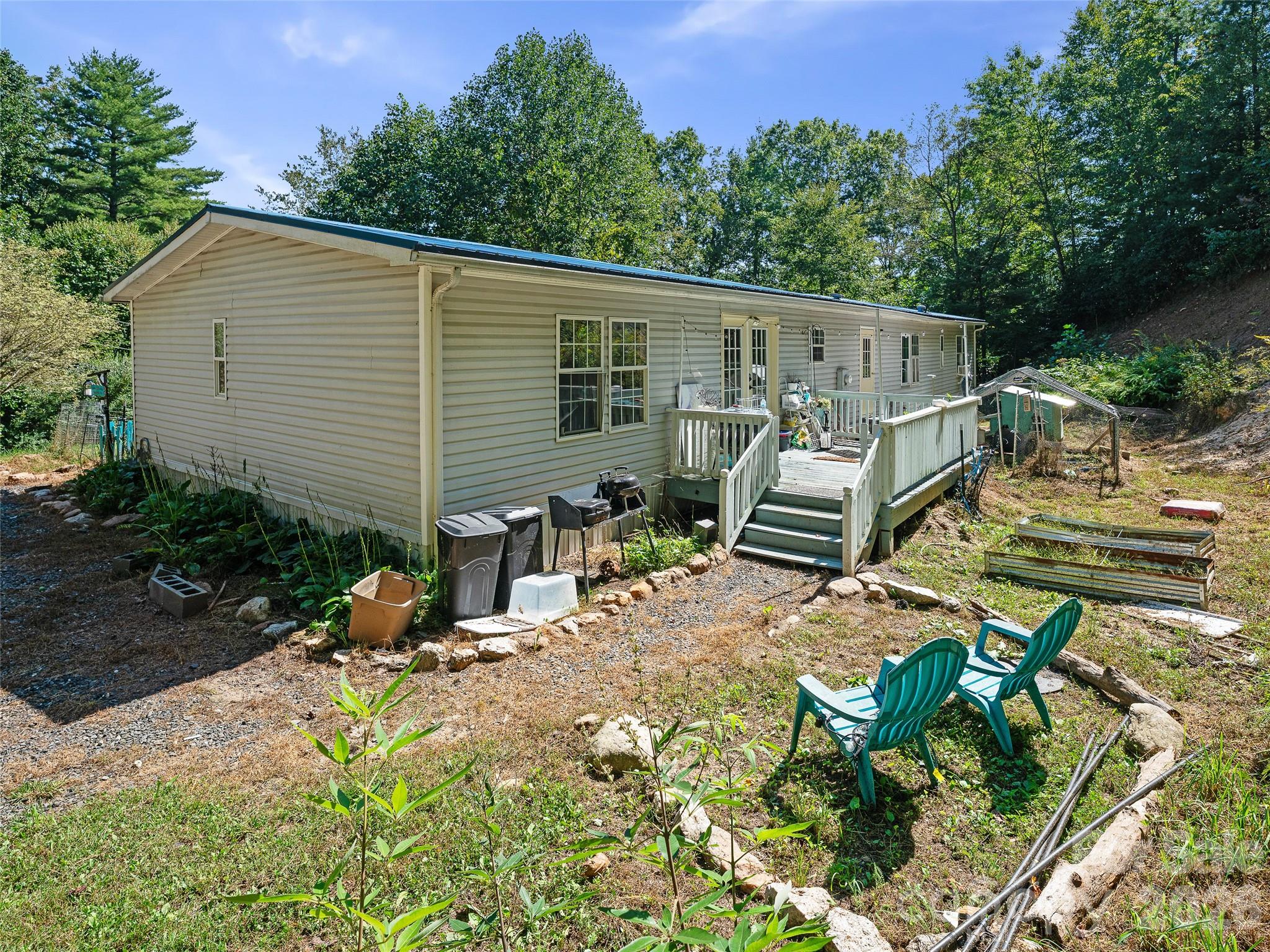 Long, light-sided home with a raised deck and wooded yard.