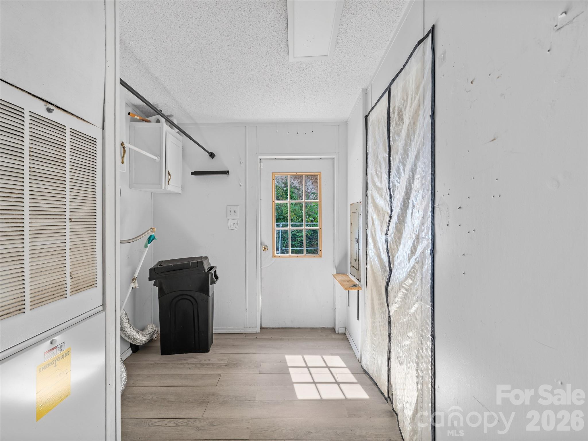 Utility room with louvered cabinet, exposed dryer vent, wall cabinets, and a windowed rear door.