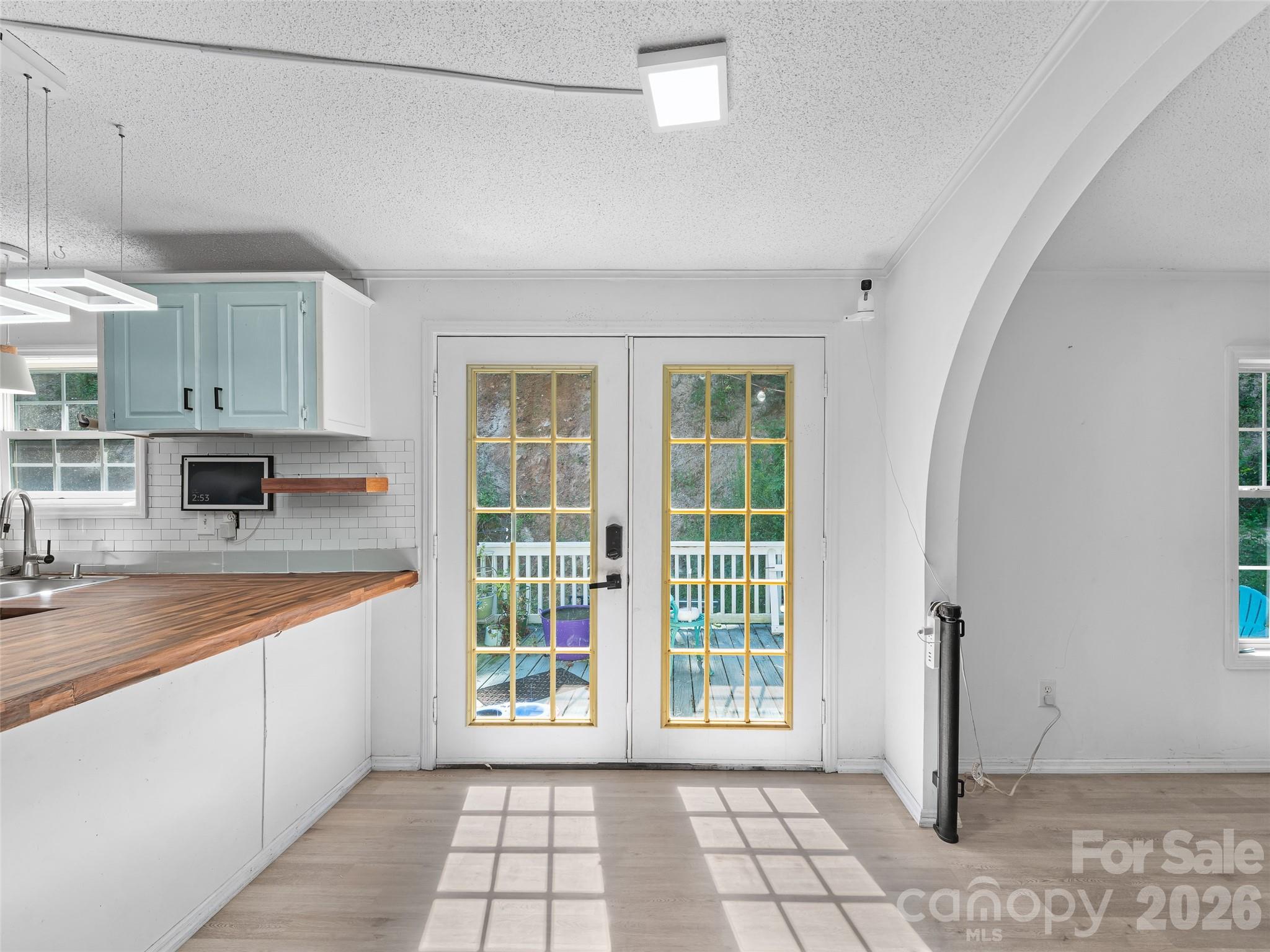 Kitchen with pale blue cabinets, wood countertop, and glass doors opening onto a deck.
