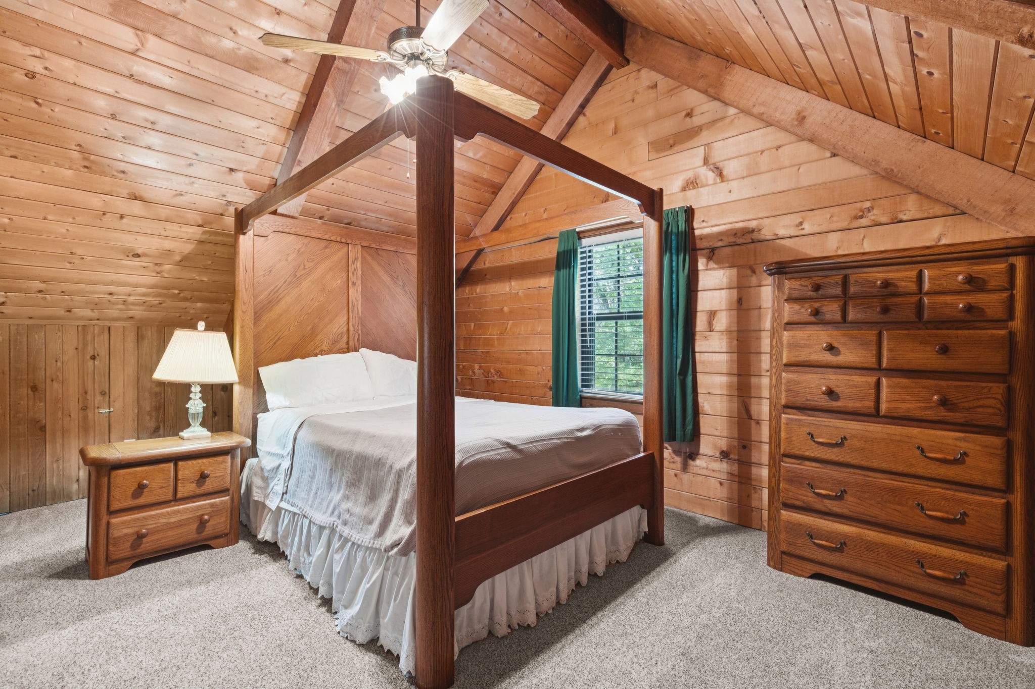 Bedroom with a wood four-poster bed, vaulted plank ceiling, and matching wooden dressers.