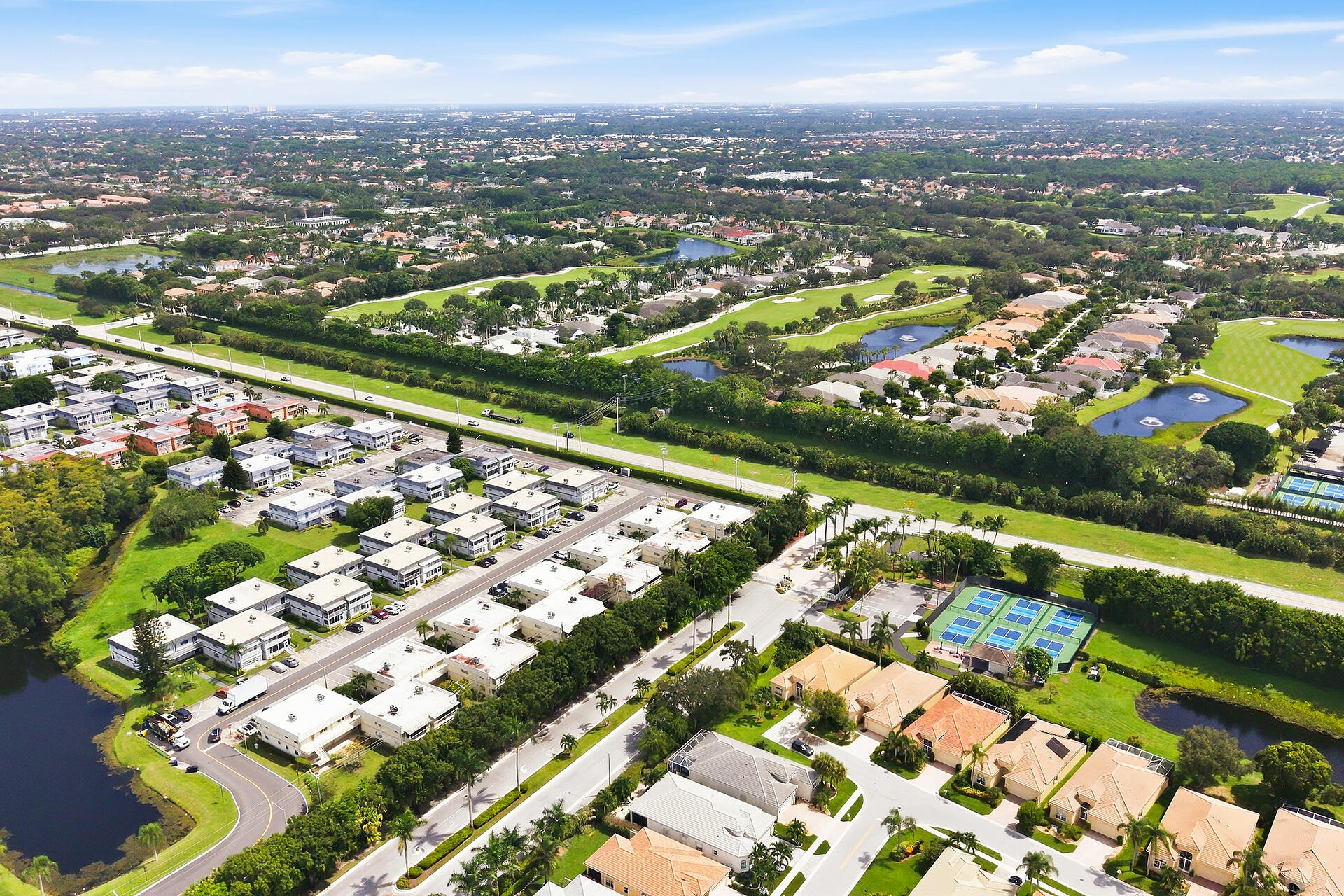 Aerial view of a residential community with a golf course, lakes, and tennis courts.