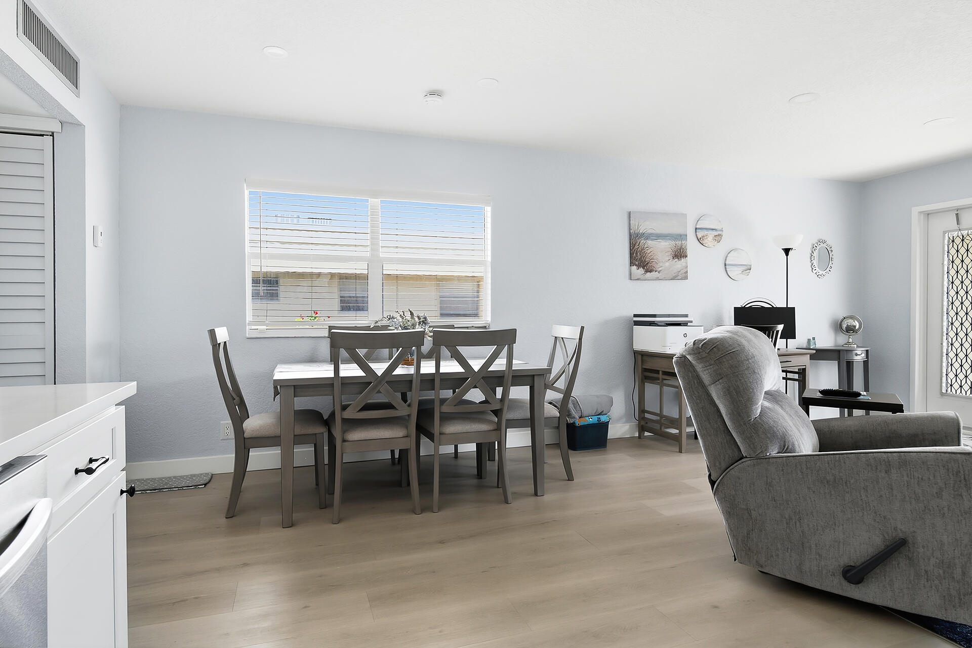 Dining and living area with a dark table, coastal wall art, and gray recliner.