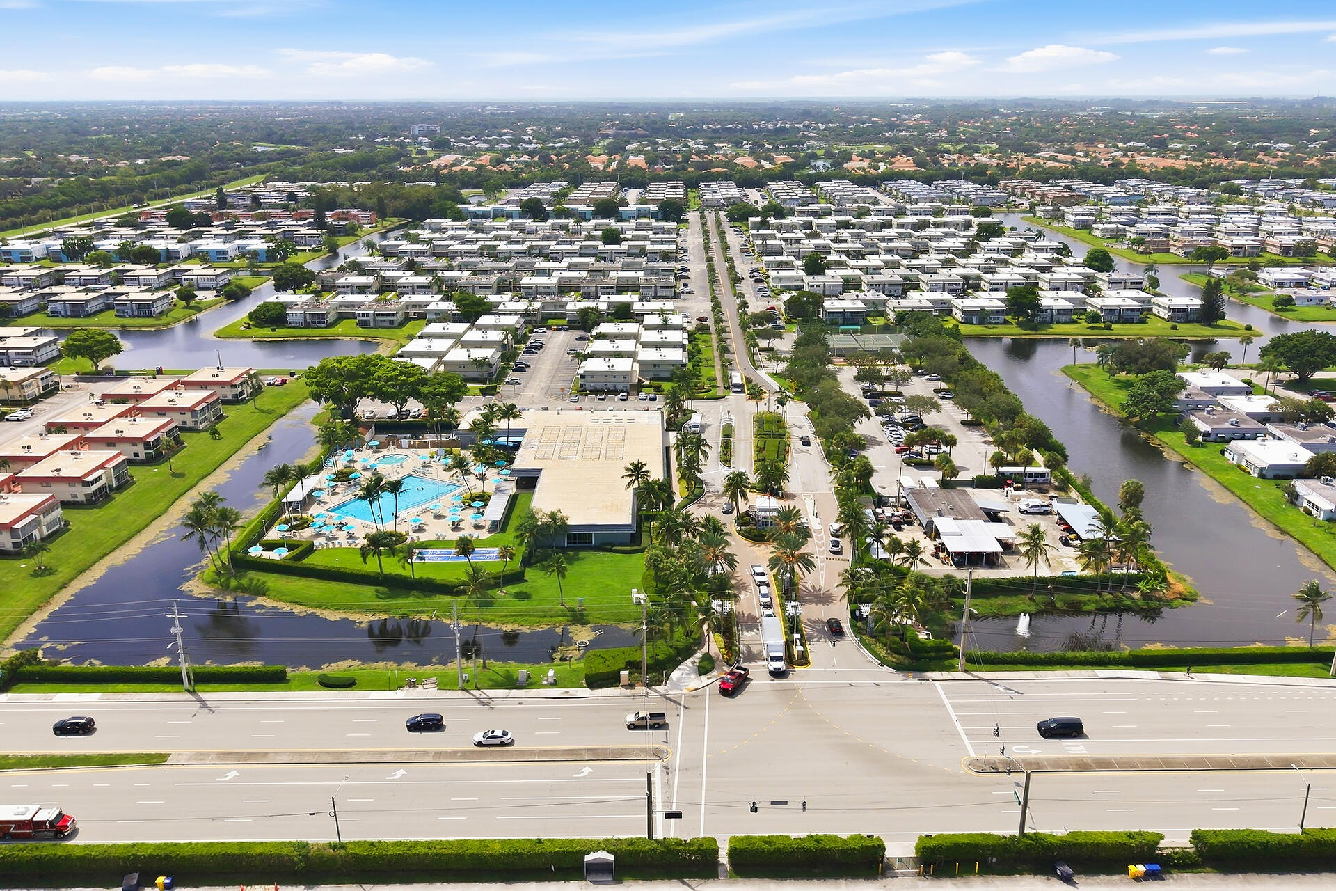 Aerial view of a residential community with a clubhouse pool, waterways, and rows of homes.