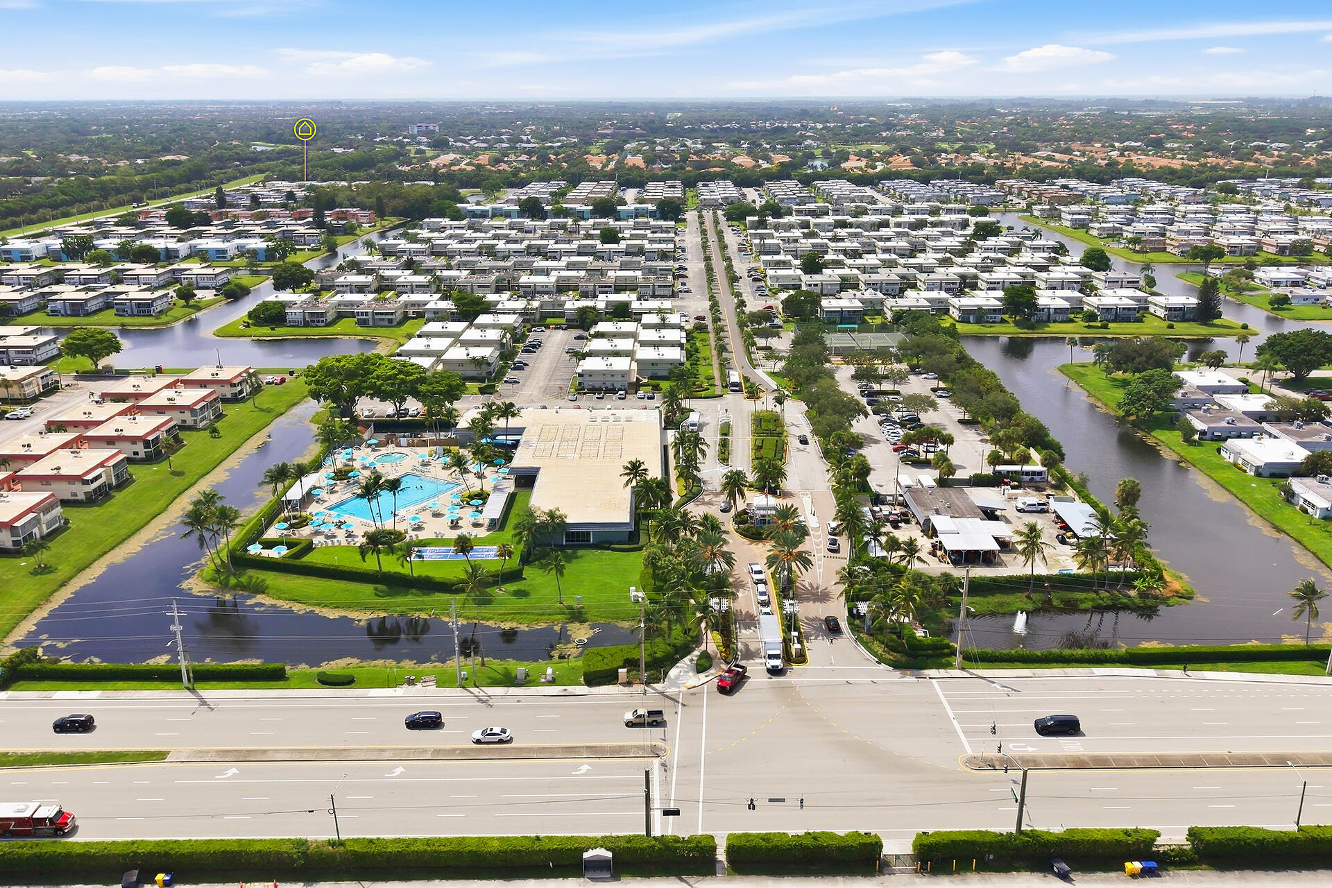 Aerial view of a residential community with pools, tennis courts, and surrounding canals.