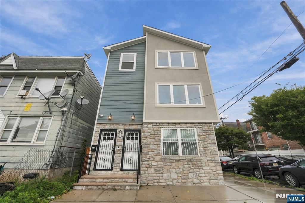 Three-story gray residential building with a stone facade and two gated entrances.