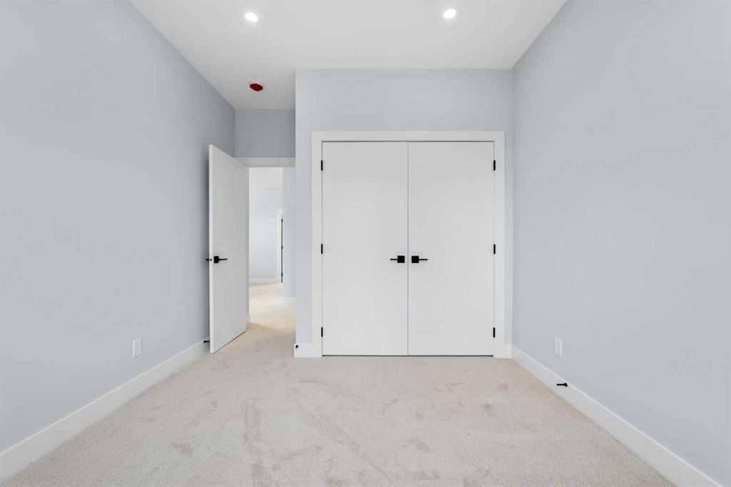 Empty carpeted bedroom with a double-door closet and open doorway.