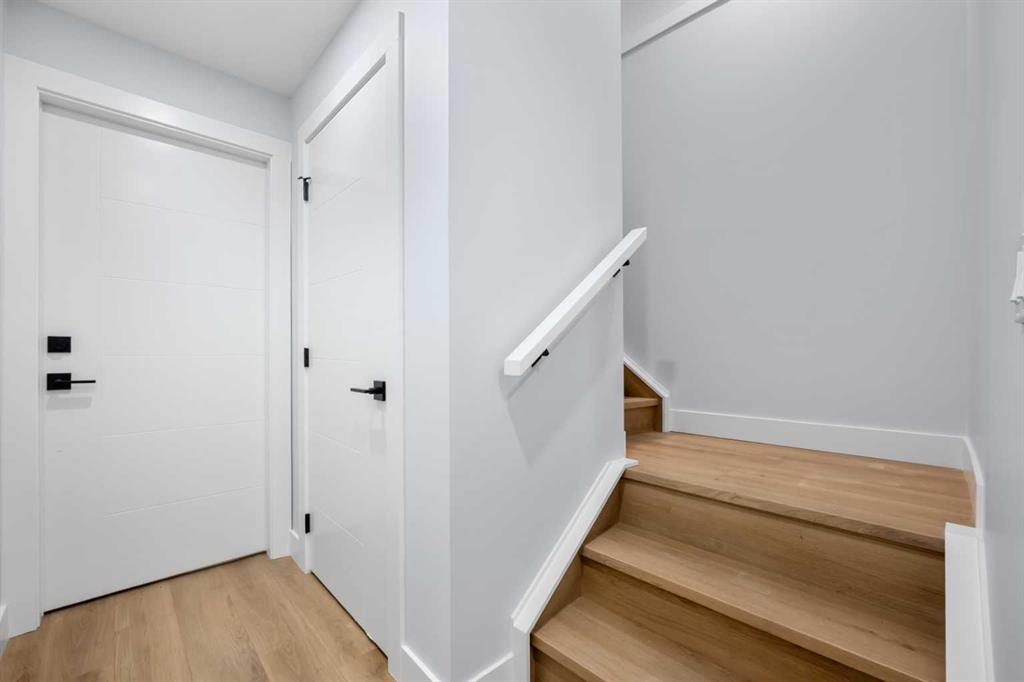 Bright hallway with white doors and light wood stairs.